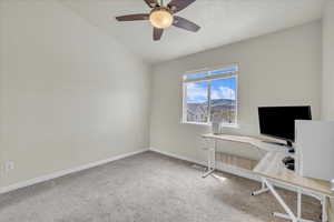 Unfurnished office featuring a ceiling fan, visible vents, vaulted ceiling, baseboards, and carpet flooring