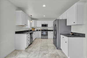 Kitchen featuring a sink, baseboards, stainless steel appliances, and white cabinetry