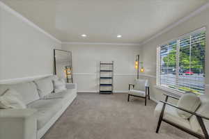 Living room with crown molding, recessed lighting, baseboards, and light carpet