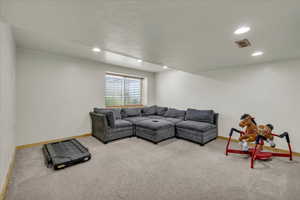 Carpeted living room with baseboards, recessed lighting, and visible vents