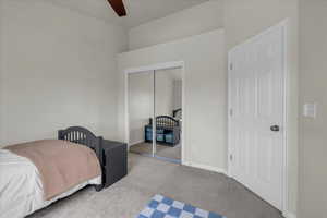 Bedroom featuring a ceiling fan, baseboards, carpet, and a closet