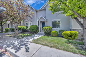 View of front of home with a front yard, stone siding, and stucco siding