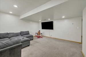 Carpeted living room featuring baseboards, electric panel, and recessed lighting