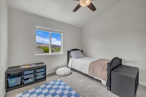Carpeted bedroom with baseboards, ceiling fan, and lofted ceiling