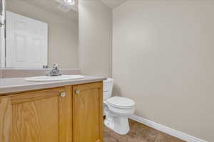 Half bathroom featuring tile patterned flooring, vanity, toilet, baseboards, and visible vents