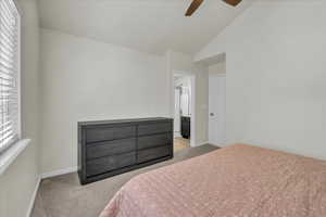 Carpeted bedroom with baseboards, ceiling fan, vaulted ceiling, and connected bathroom