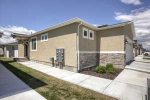 View of property exterior featuring an attached garage, stucco siding, and stone siding