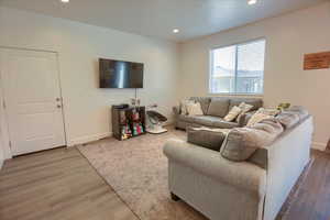 Living area with baseboards, recessed lighting, and light wood-style flooring
