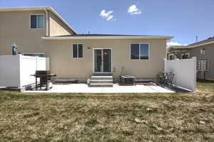Back of house featuring fence, a lawn, and a patio area