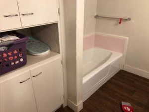Bathroom with baseboards, a garden tub, and wood finished floors