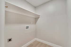 Washroom with laundry area, baseboards, hookup for a washing machine, light wood-style flooring, and hookup for an electric dryer