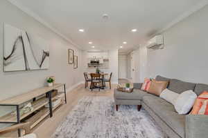 Living area featuring crown molding, light wood-style floors, recessed lighting, and a wall mounted air conditioner
