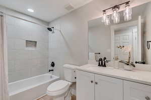 Full bathroom featuring vanity, shower / bath combo, toilet, and visible vents