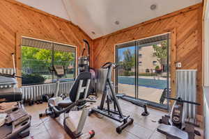 Exercise area featuring lofted ceiling, wood walls, and a wealth of natural light