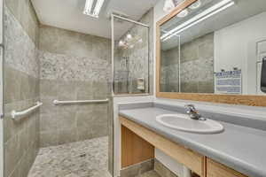 Bathroom featuring vanity, tile patterned flooring, and tiled shower