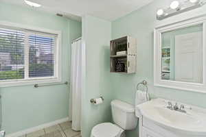 Bathroom featuring vanity, toilet, shower, and tile patterned floors