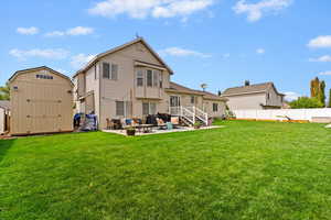 Back of house featuring a top-of-the-line outdoor shed, fence, a patio area, and a well-maintained lawn.