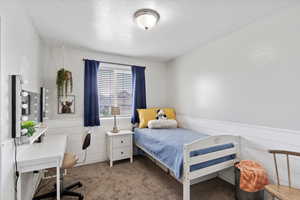 Bedroom featuring wainscoting and carpet flooring.