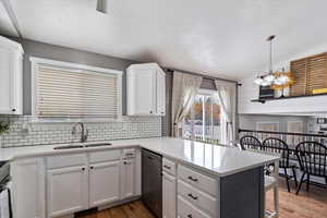 Kitchen featuring updated backsplash, appliances with stainless steel finishes, white cabinets, and a peninsula