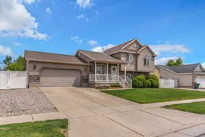 Split level home featuring a gate, stucco siding, and stone siding with room for rv or trailer parking.