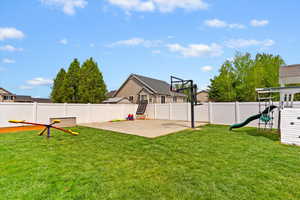 View of yard featuring a playground, a fenced backyard, and basketball pad.