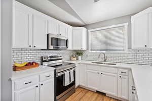 Kitchen featuring quartz countertops, stainless steel appliances, and white cabinetry