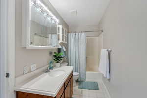 Bathroom with vanity, toilet, tile patterned floors, baseboards, and shower / tub combo