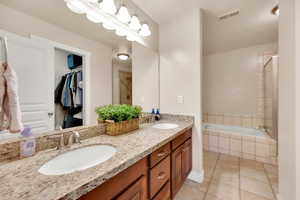 Primary Bathroom featuring a relaxing tiled tub, a sink, tile patterned floors, and visible vents