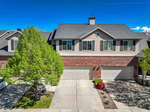 Multi unit property with driveway, roof with shingles, brick siding, an attached garage, and stucco siding
