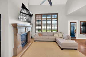 Living area with plenty of natural light, a fireplace, ceiling fan, and wood finished floors