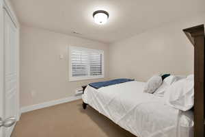 Bedroom with visible vents, a baseboard radiator, baseboards, and light carpet
