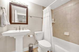 Full bath featuring toilet, baseboards, and shower / bath combo with shower curtain