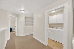 Laundry area featuring cabinet space, separate washer and dryer, built in shelves, baseboards, and visible vents