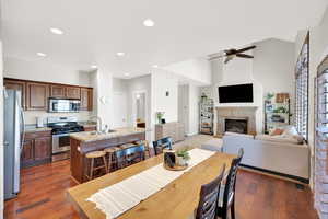 Dining room featuring a glass covered fireplace, recessed lighting, ceiling fan, and dark wood-style flooring