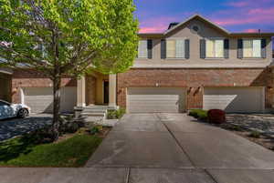 View of front of house featuring a garage, stucco siding, driveway, and brick siding