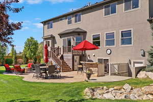 Rear view of house with a lawn, stucco siding, a patio area, and stairway