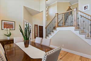 Dining room featuring crown molding, stairs, wood finished floors, baseboards, and a high ceiling