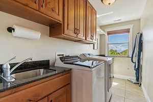 Washroom with visible vents, washing machine and clothes dryer, a sink, cabinet space, and light tile patterned floors