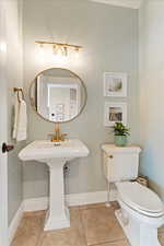 Half bath featuring baseboards, tile patterned flooring, and toilet