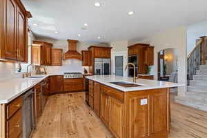 Kitchen featuring a sink, appliances with stainless steel finishes, custom range hood, and beverage cooler