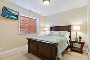 Bedroom featuring baseboards, visible vents, and light colored carpet