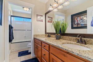 Full bath featuring a sink, tile patterned flooring, toilet, and double vanity