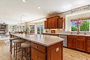 Kitchen with light wood-style floors, open floor plan, light countertops, a sink, and dishwasher