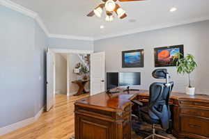 Office area featuring light wood-style floors, crown molding, baseboards, and ceiling fan
