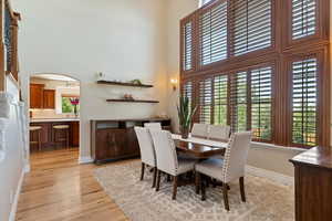 Dining area featuring a high ceiling, plenty of natural light, baseboards, and light wood-type flooring