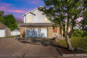 Traditional home with brick siding, a garage, fence, and driveway