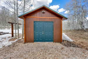 Snow covered structure featuring a storage unit and an outdoor structure