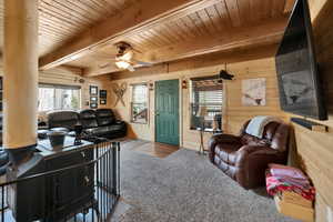 Living area featuring carpet floors, wooden walls, and wooden ceiling