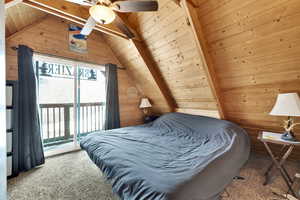 Bedroom with carpet flooring, wooden walls, access to outside, lofted ceiling with beams, and wooden ceiling