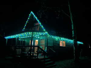 Back of house at night with a wooden deck and log veneer siding